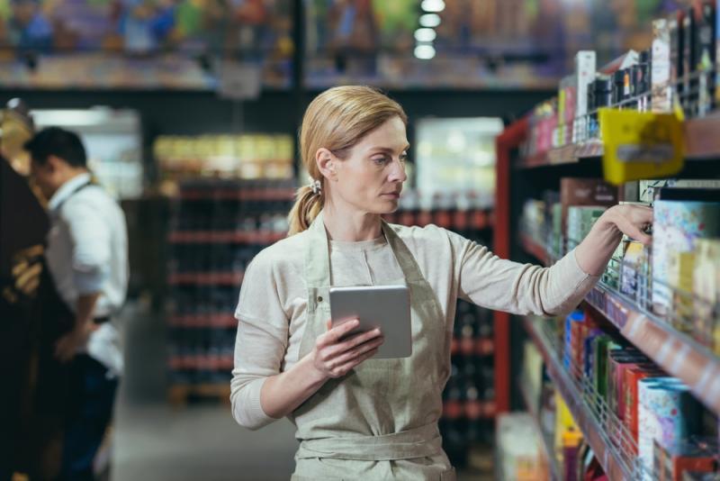 Supermarket employee using tablet while checking inventory
