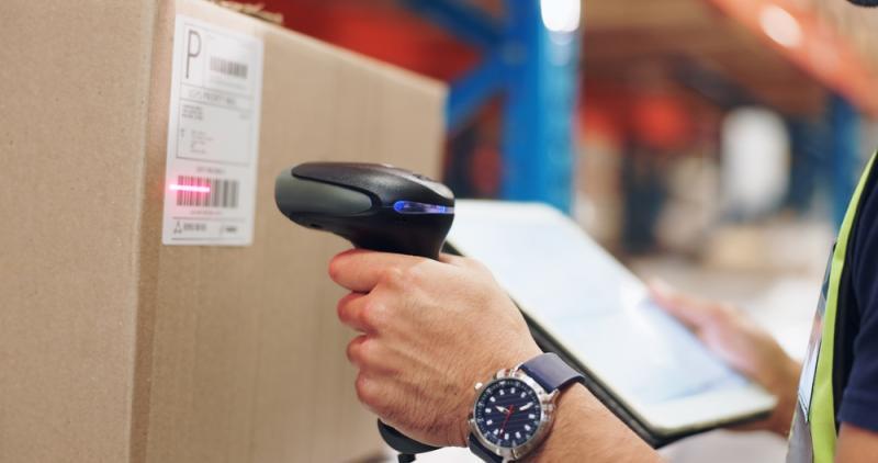 A hand scanning a bar code on the side of a box.