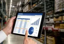 Hands pointing to a computer tablet showing charts