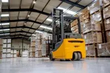 A forklift in a warehouse stacked high with palletts.